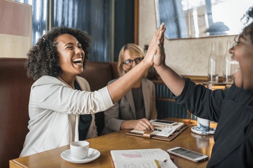 three friends doing a high five at a meeting