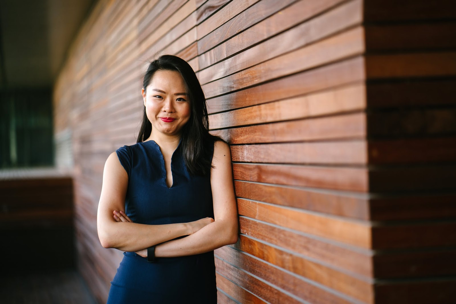 woman in blue dress posing against wooden partition thinking about changing jobs advice
