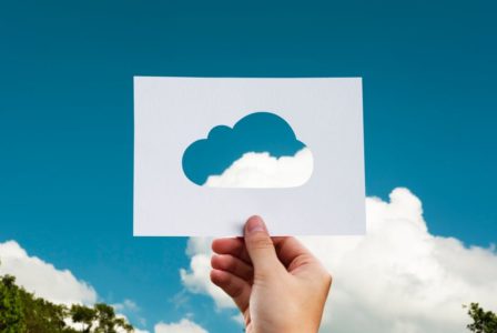 hand holding cutout cloud against sky background