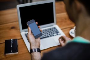 man with iphone at computer