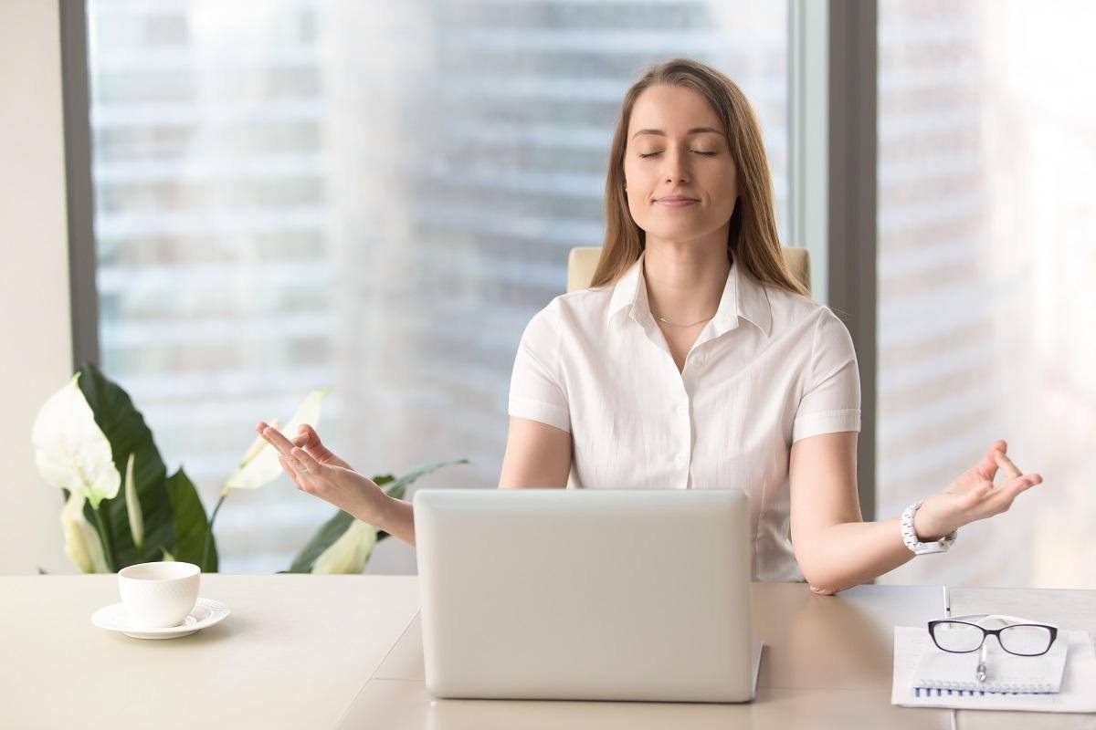 woman meditating before a laptop reduce stress immediately