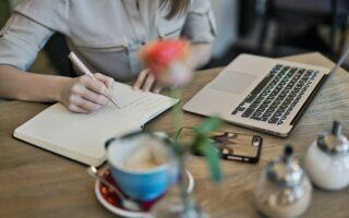 keyboard and woman writing on notepad content writing