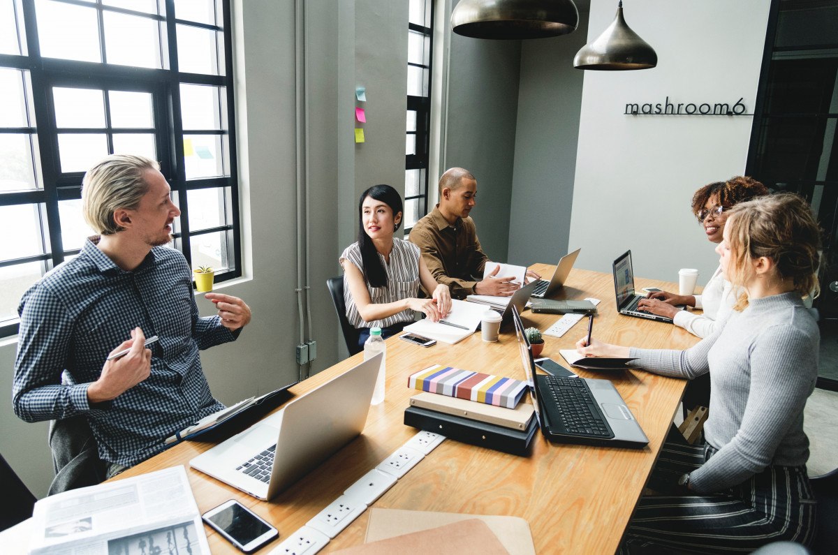 office environment tips as employees discuss at desk with open laptops