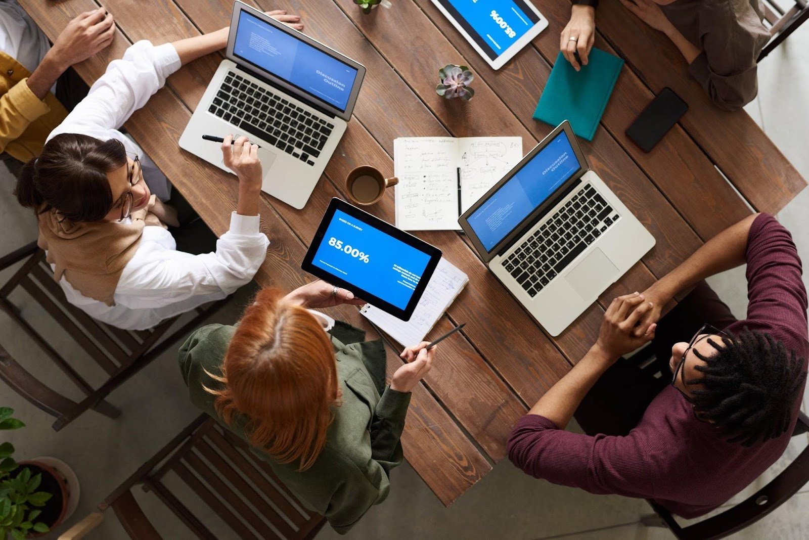 top-view-photo-of-group-of-people-using-macbook-while-discussing-employee health and safety