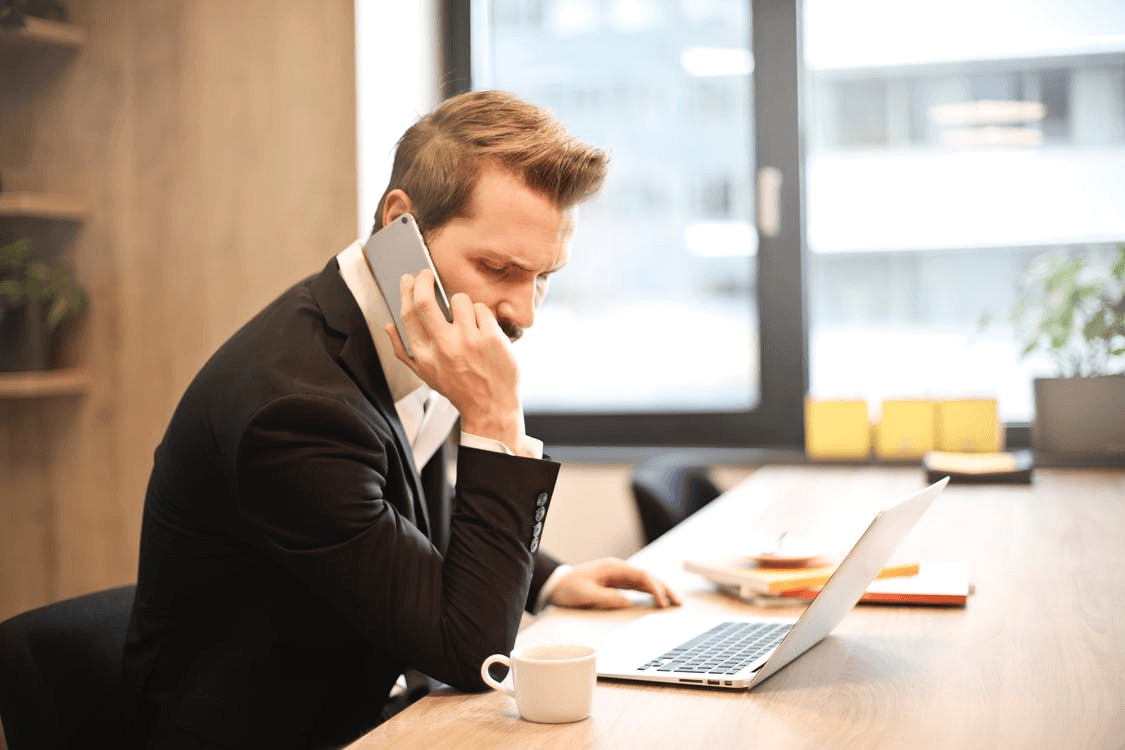 using emergency business contacts list man-having-a-phone-call-in-front-of-a-laptop