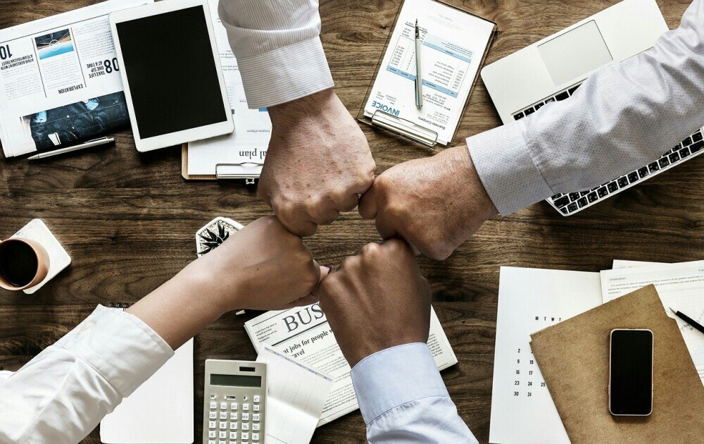 four fists doing a fist bump across a work table